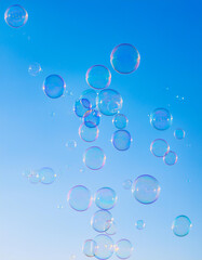 Soap bubbles floating in blue sky. Abstract backdrop.