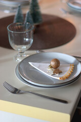 Table set for Christmas meal with plates, glasses, holiday decorations, lit candles and wine. Selective focus.