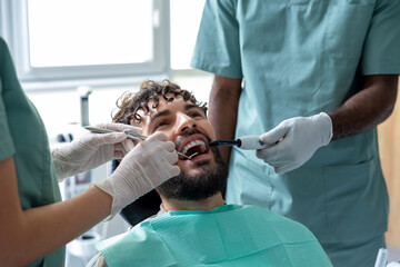 Man patient during visit to the clinic for routine cavity checkup sitting in treatment chair
