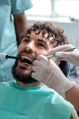 Male dentist performing orthodontic checkup on patient in modern dental clinic