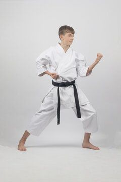 Fifteen year old male teenage karate black belt in long stance doing a body block, studio shot against a white background