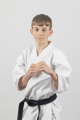 Fifteen year old male teenage karate black belt ready to spar, studio shot against a white...