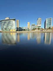 Modern buildings and landmarks next to the water with a clear blue sky background. Taken in Salford...