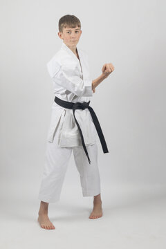 Fifteen year old male teenage karate black bel in sanchin stance doing a body block , studio shot against a white background