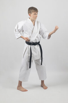 Fifteen year old male teenage karate black bel in sanchin stance doing a body block , studio shot against a white background
