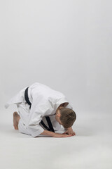 Fifteen year old male teenage karate black belt bowing, studio shot against a white background