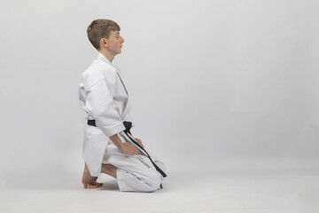 Obraz premium Fifteen year old male teenage karate black belt kneeling eyes closed, studio shot against a white background