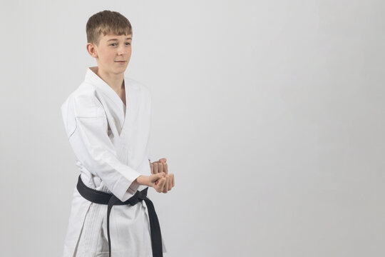 Fifteen year old male teenage karate black belt peforming a short punch, studio shot against a white background