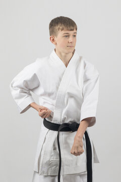 Fifteen year old male teenage karate black belt doing a groin block, studio shot against a white background