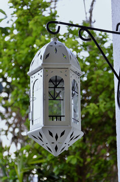 A beautiful and crafted white Moroccan lantern hanging in the garden