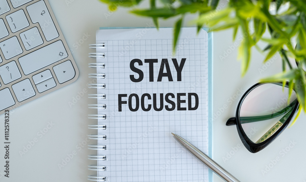 Fototapete stay focused on your goals. with a text message in a notepad, clock and pen.