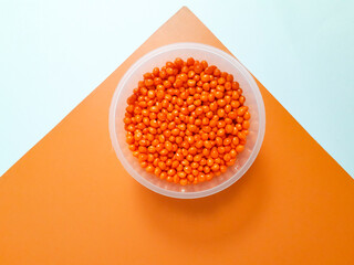 Orange masterbatch granules in plastic cup on white and orange background,color pigment carrier polymer in plastic industry.Suitable for plastic company catalog design