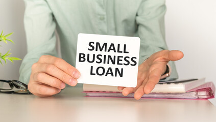 SMALL BUSINESS LOAN text on paper with chart and office tools , business concept
