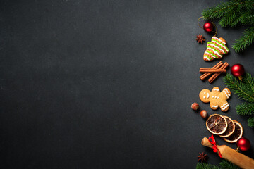 Christmas food background at black. Gingerbread cookies, spices and Christmas decorations. Flat lay...
