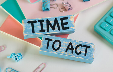 Time To Act text concept written on wooden cubes blocks lying on a light table next to calculator and pen