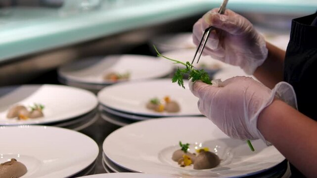 molecular cuisine. chef decorates with parsley leaves many identical portions of mushroom pate in molecular cuisine work with tweezers neat work