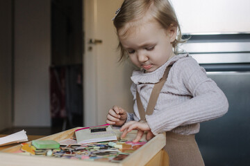 Portrait of toddler girl playing with toys in playroom. Adorable two years old girl at home, enjoying creative playtime in a bright, cozy environment. Generation alpha concept. Part of a series