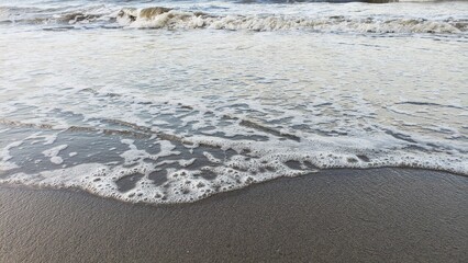 Foamy Sea Waves Receding on a Sandy Beach