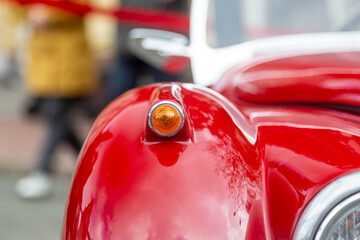 Yellow blinker on the front of red classic car