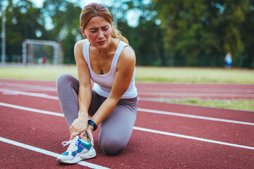 Woman Injured on Running Track Holding Ankle in Painful Expression