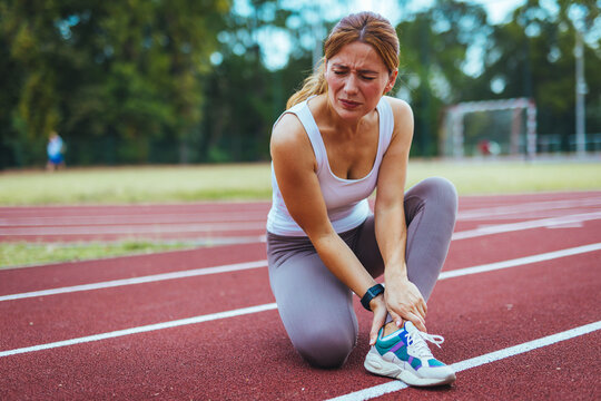 Female Runner Experiencing Ankle Pain On Outdoor Track Field
