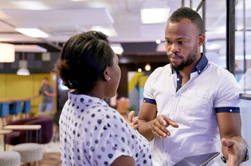 Obraz premium Attractive African American male model discussing with professional female agent in large modern office room