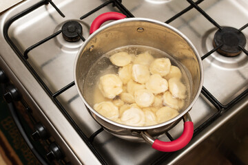 Ravioli in a saucepan in boiling water. Cooking ravioli filled with minced meat in a steel pan.