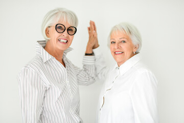 Portrait of two elderly woman over grey background.