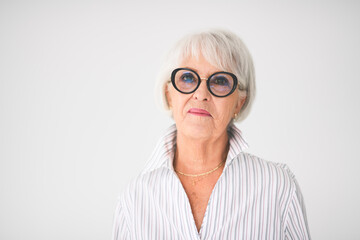 Portrait of elderly woman in eyeglasses over grey background.