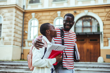 Friends Smiling While Walking Together on University Campus Holding Books