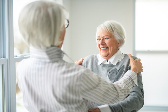 Portrait of two elderly woman over grey background hug together