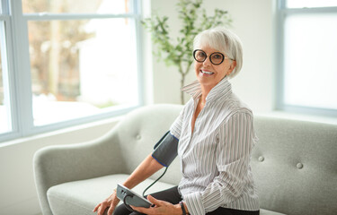 Portrait of elderly woman using Blood Pressure Monitor