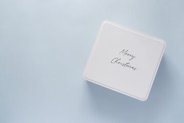 White Christmas gift box on light blue background with space for text or design. Present for Christmas or Saint Nicholas Day on a minimal background, top view