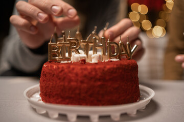 Happy birthday cake red velvet decorated with gold candles on the blurred lights background
