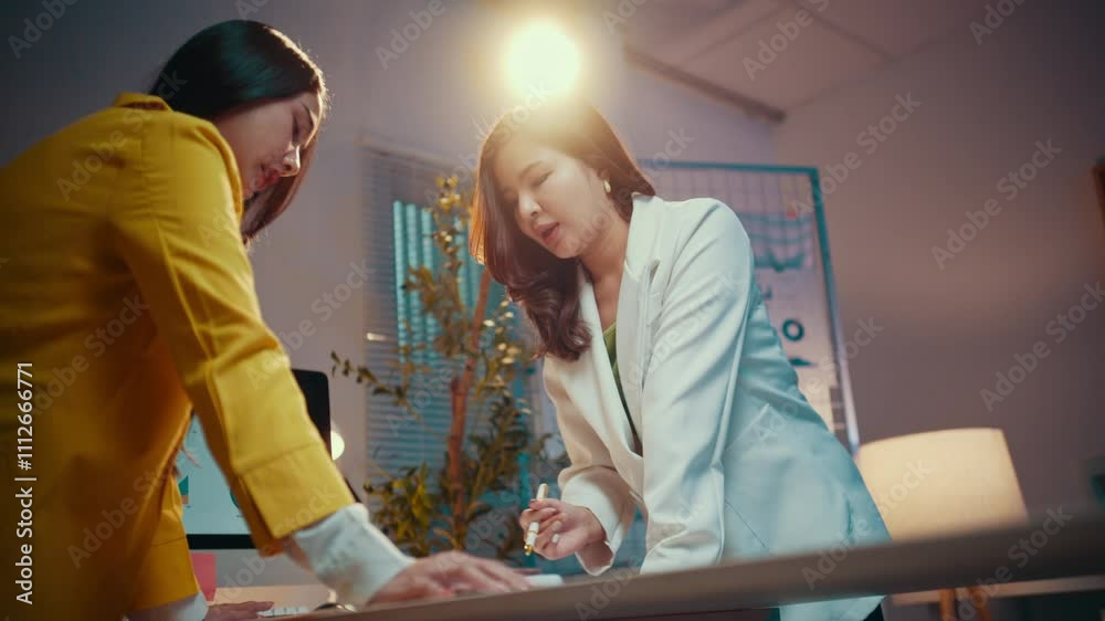 Aufkleber two businesswomen engage in a work discussion at their office desk during the night. they review pap