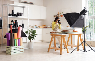Young female photographer taking picture of food in modern kitchen