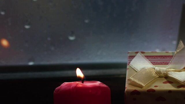 Holy Christmas New Year Eve Decoration and Gift Boxes on Candle Light Near the Window Glass in Rainy Day