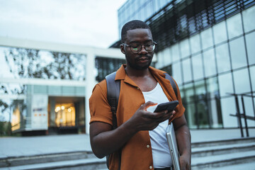 Young Man Using Smartphone Outside Modern Office Building