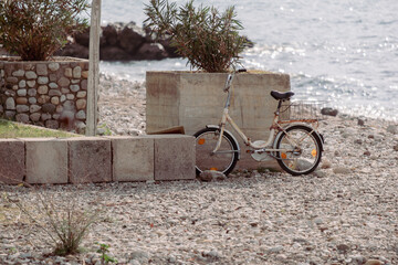 A bicycle is parked on a rocky beach near a wall