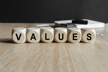 Writing the word ‘Values’ on wooden cubes. Beautiful wooden table, black background. Business...