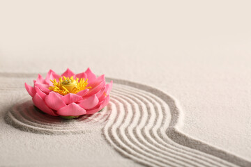 Beautiful flower on light sand with pattern. Zen concept