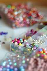 Hand figurine, colorful friendship bracelets, necklaces, various beads and DIY supplies on the table. Making jewelry at home. Selective focus.