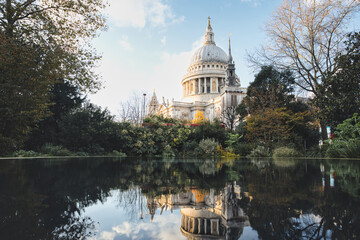 St. Paul's cathedral reflected in a tranquil pond surrounded by autumn trees in a london park,...