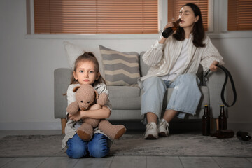 Sad little girl with toy bear and her drunk mother at home. Domestic violence concept