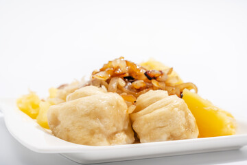 A plate of food with a variety of different foods on it. The plate is white and the food is brown