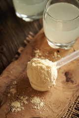 Whey protein powder in a scoop with fresh natural whey on a table