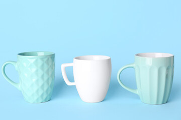 Different ceramic cups on blue background