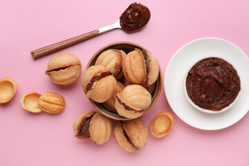 Bowl with sweet walnut shaped cookies with boiled condensed milk on pink background