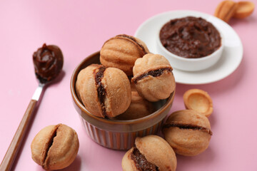 Bowl with sweet walnut shaped cookies with boiled condensed milk on pink background