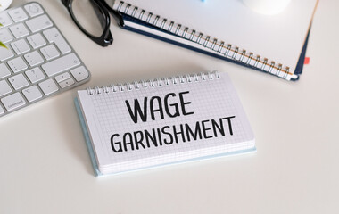 Wage Garnishment T, text on white paper on black envelope near financial charts